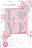 This anniversary card offers a gentle, romantic statement, blending soft pastel pinks and silvery greys into a design that feels both intimate and refined, much like a carefully chosen bouquet delivered to a doorstep off Chislehurst Road. The visual centrepiece is the word LOVE, rendered in soft, raised glitter that gives each letter a subtle three-dimensional presence. The letters are primarily blush pink, with the edges accented by pale, shimmering glitter. In place of the letter O sits a small, shimmering heart, textured in brighter silver, making it the brightest point on the card and naturally drawing the eye. The raised finish appears smooth but distinct under the light, suggesting a pleasant tactile sensation when touched. Around this focal word, a halo of delicate flowers unfurls, painted in blush, mauve and ivory tones with translucent, watercolour-style shading. These blossoms are outlined with fine, flowing lines that curl into slender vines, echoing the organic curves of climbing roses. Tiny flourishes-drifting petals, soft decorative swirls and subtle, almost-translucent butterflies-thread their way through the design, adding motion and a sense of whimsical grace akin to an English spring garden after rain. The phrases On Our Anniversary and I love you today and always appear in an understated, elegant script, the letters slender and slightly slanted, complementing the curves of the floral motifs. The overall layout feels balanced, with the denser decoration around the word LOVE gradually fading into more open space at the edges, creating a calm, breathable composition. This card would sit beautifully beside an anniversary arrangement from Chislehurst Flowers, carrying a sentiment that is soft as a whisper yet profoundly heartfelt, perfect for marking a shared journey of love and loyalty.